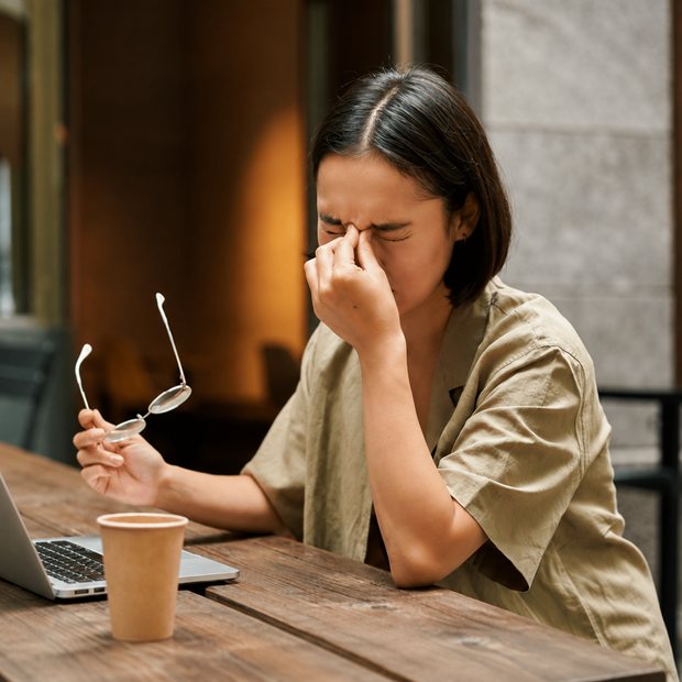 Người phụ nữ bỏ kính, day mắt khi làm việc với máy tính